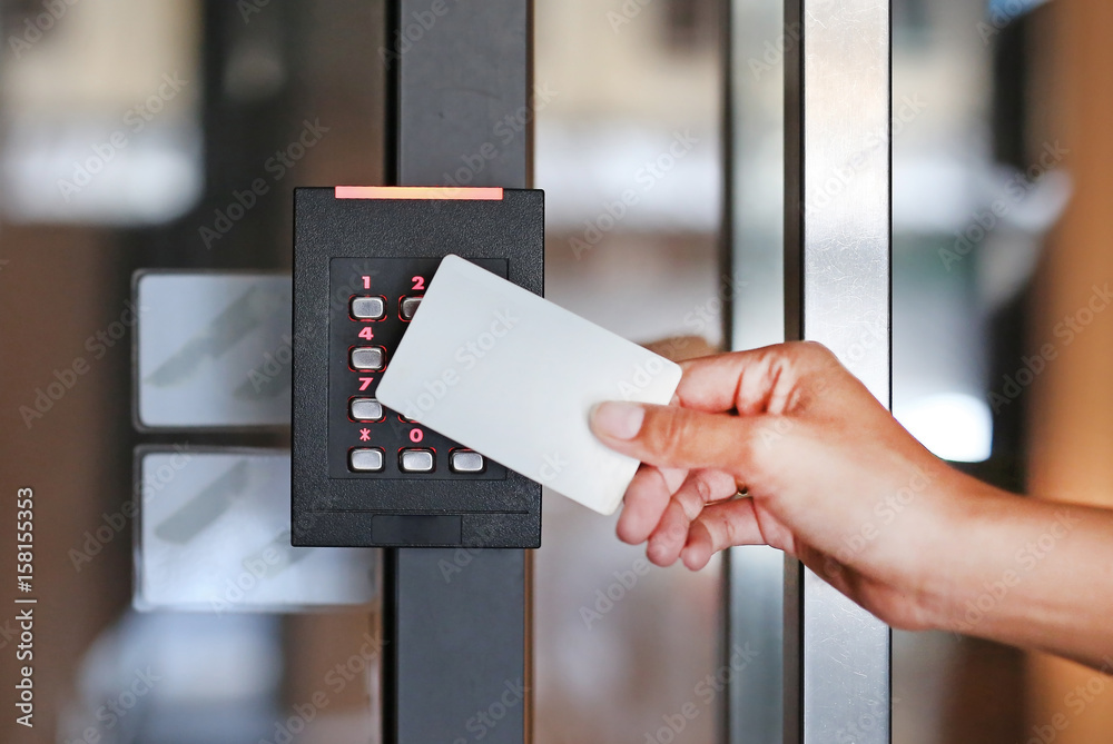 Door access control - young woman holding a key card to lock and unlock door. Access Control Systems.