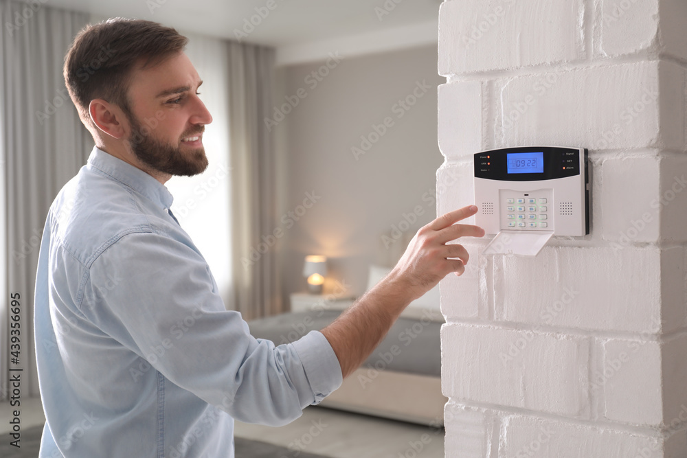 Man entering code on security alarm system at home. Top 10 reasons to have a home security system