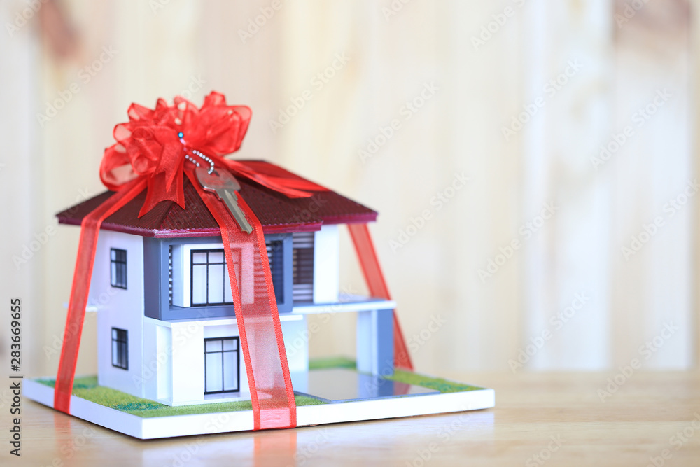 Real estate and Gift new home concept,Model house with Red ribbon and key on white background. Christmas home security