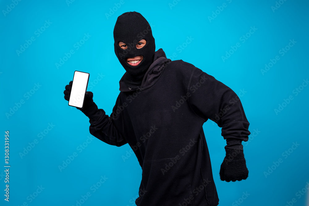 Evil Burglar Wearing Mask Showing Smartphone While Walking Isolated On Blue Background. Reasons why burglars target homes.