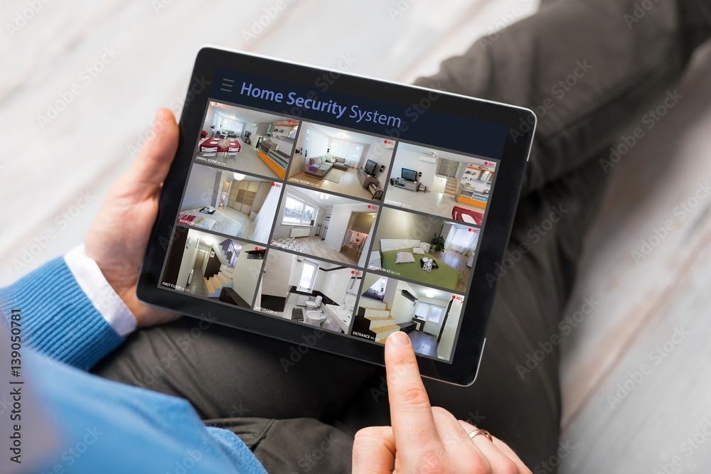 Man looking at home security cameras on tablet computer. Wireless home security