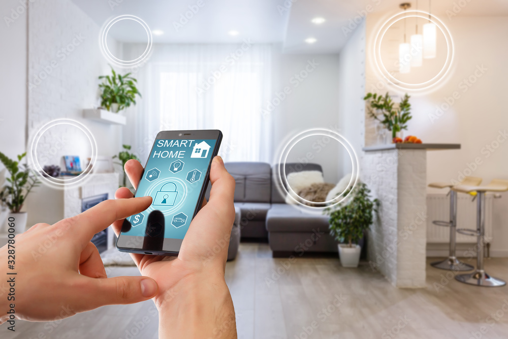 Smart home technology interface on smartphone app screen with augmented reality (AR) view of internet of things (IOT) connected objects in the apartment interior, person holding device. Home automation