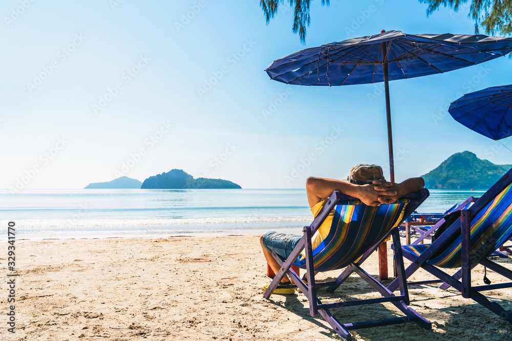 Summer lifestyle Asian man traveler relaxing on beach chair in front of vacation exotic beach, Attraction place leisure tourist travel Hua Hin Thailand holiday trip, Tourism beautiful destination Asia