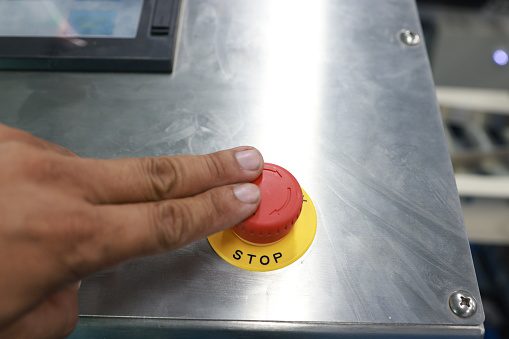 Hand activating emergency stop button.