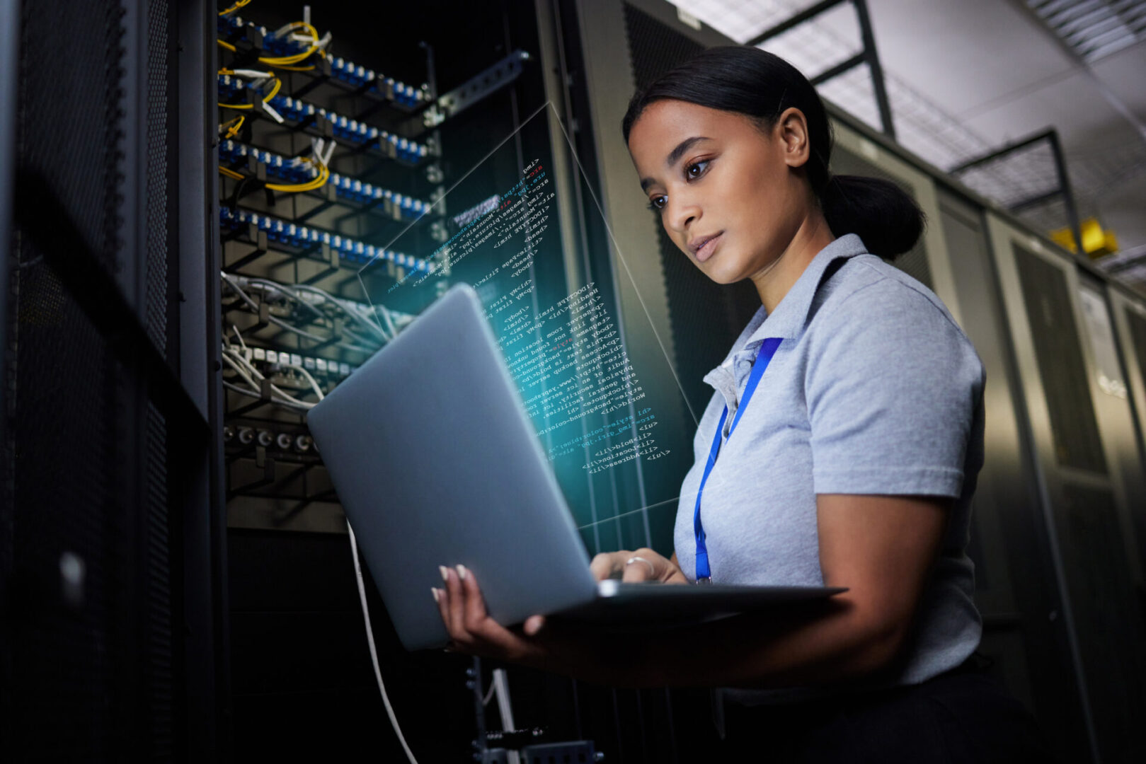 Woman working on laptop in server room.
