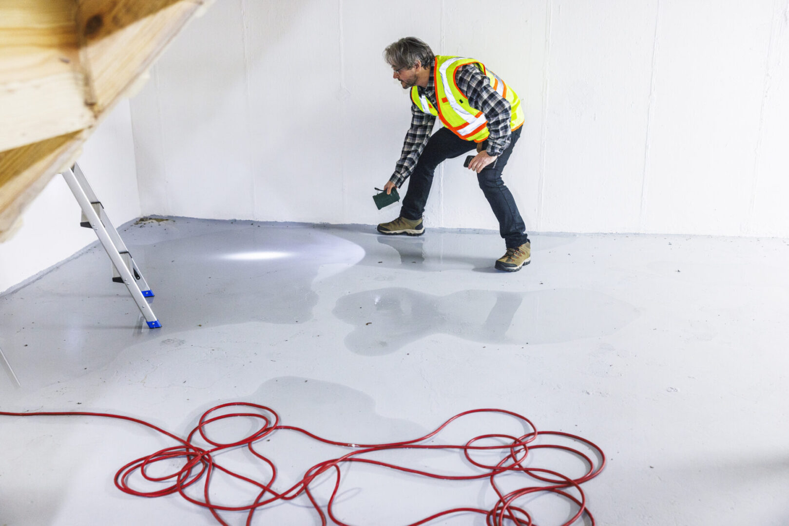 Worker inspecting wet floor with flashlight