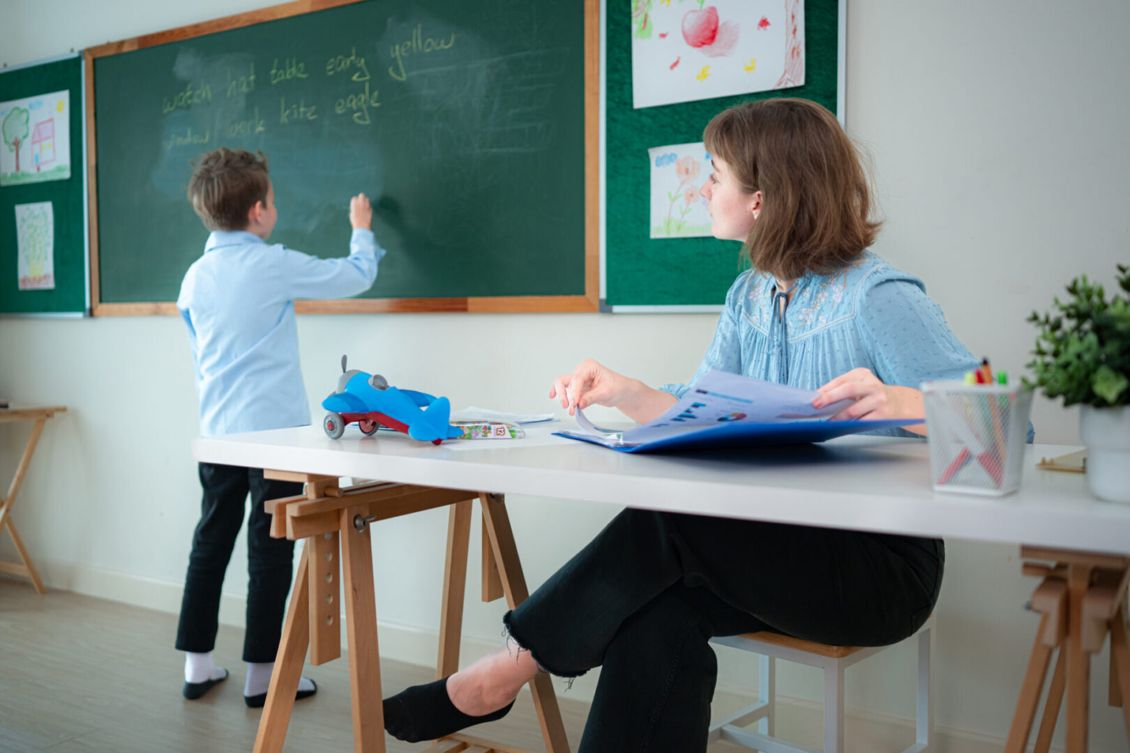 Child writing on chalkboard in classroom