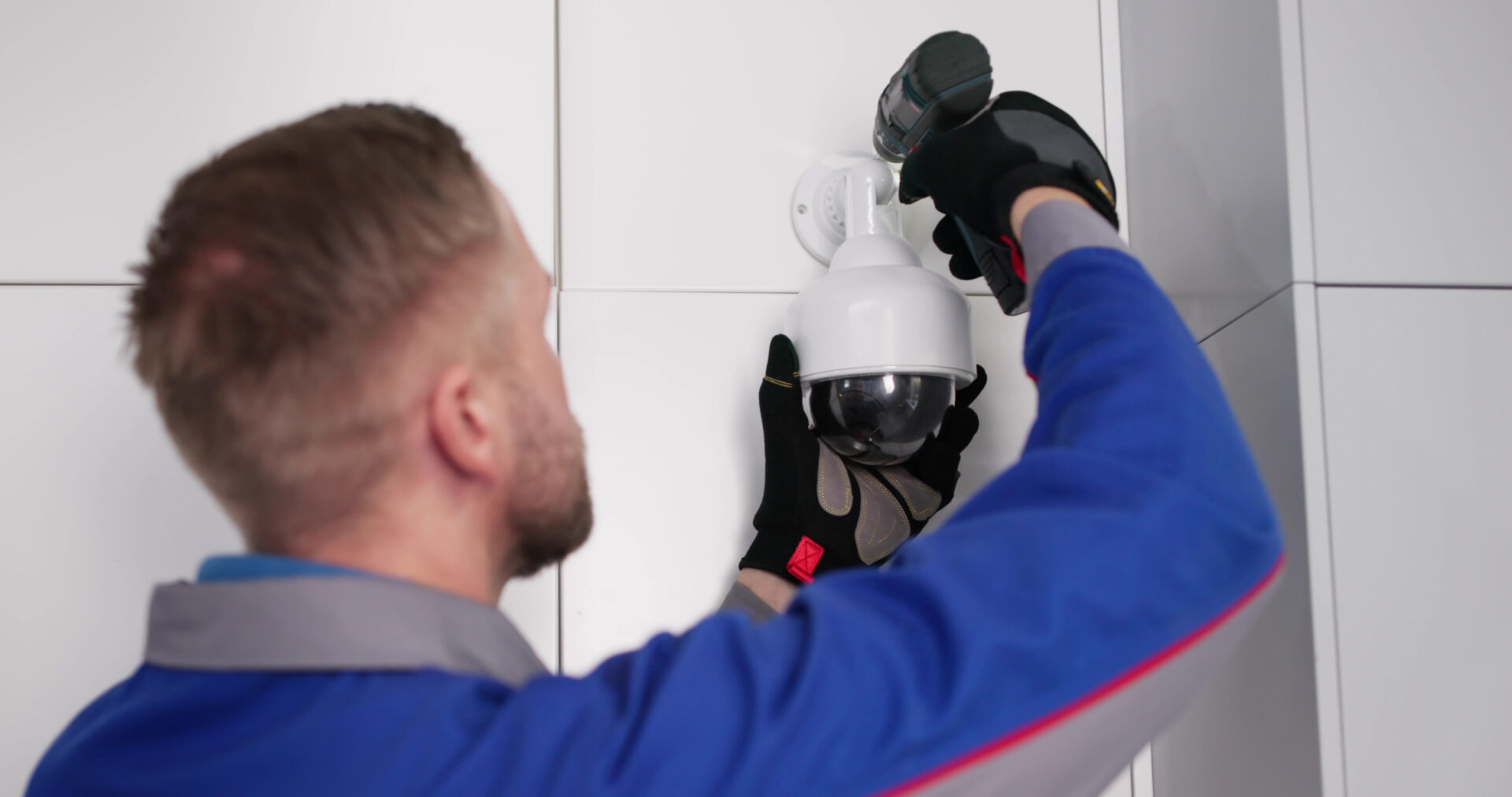 Worker securing CCTV camera with drill