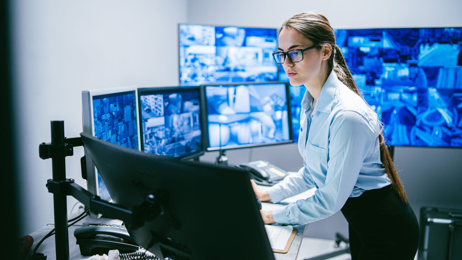 Woman monitoring security screens in control room