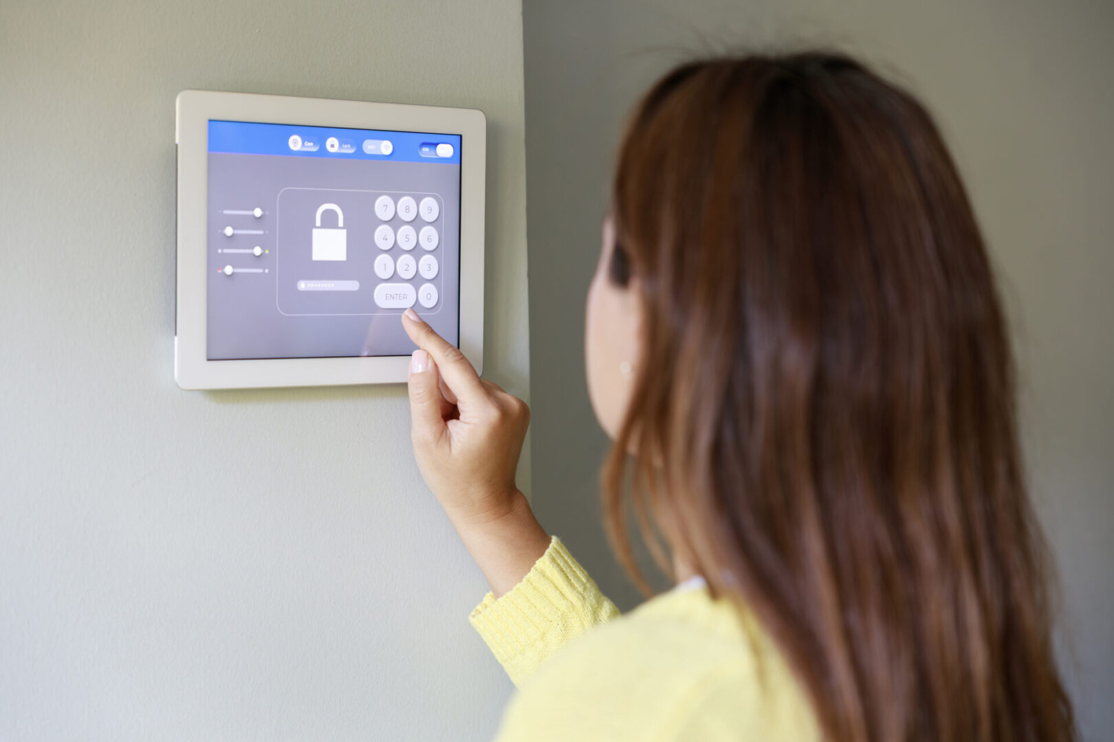 Woman entering code on a home security keypad.
